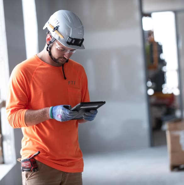 FTI team member wearing PPE using a tablet on job site