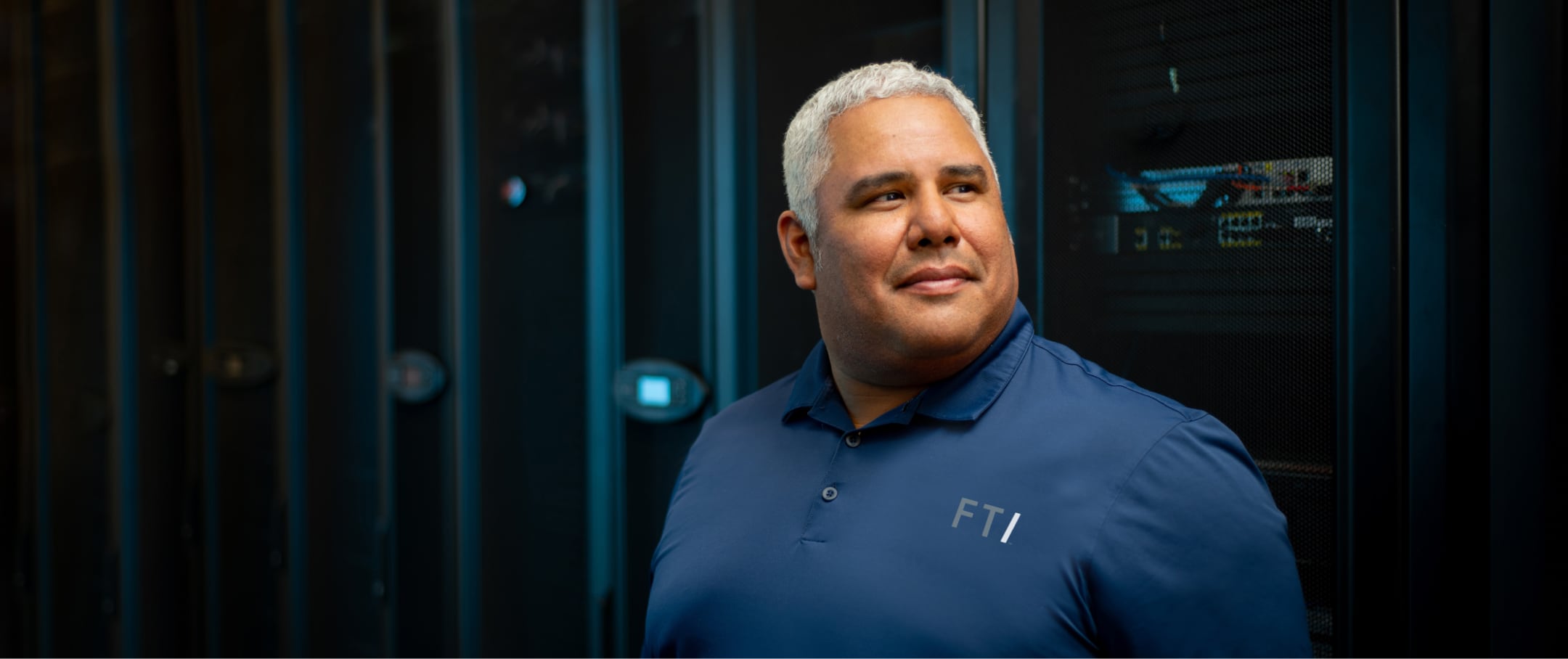 FTI team member smiling in front of technology