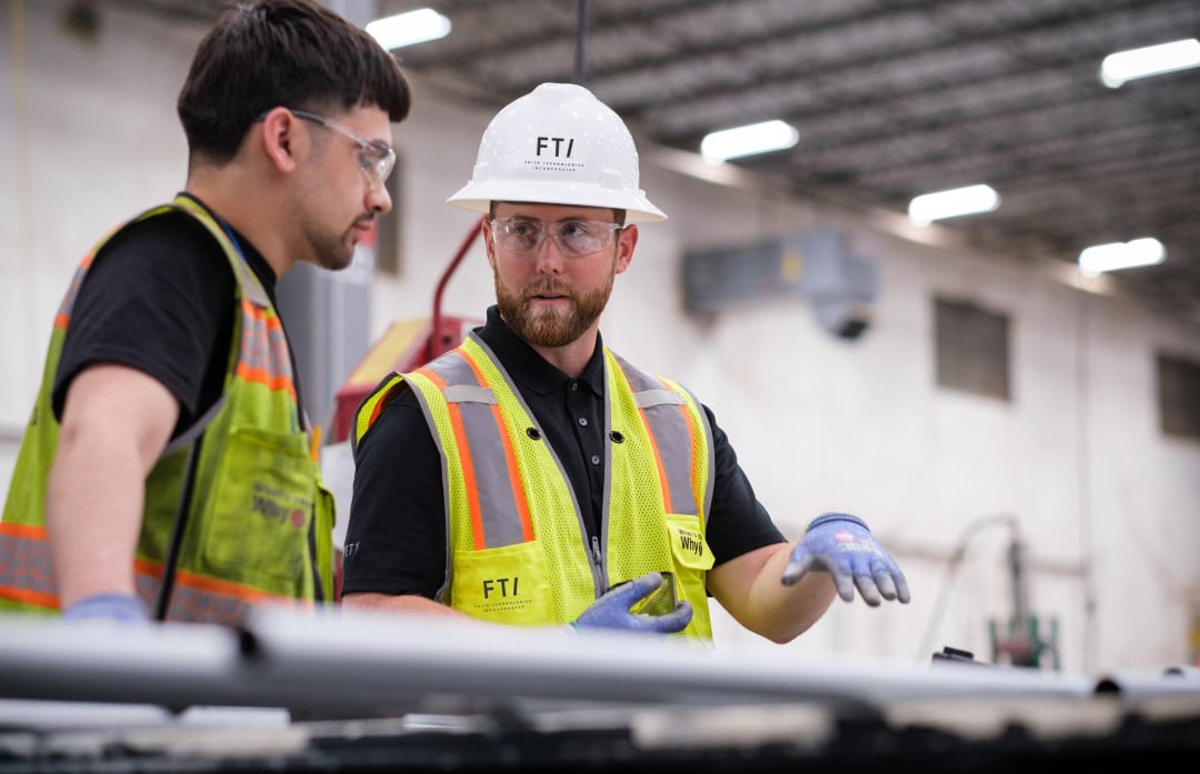 Two FTI team members collaborating in a manufacturing facility