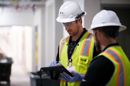FTI Team Members Wearing PPE While Collaborating on an iPad.